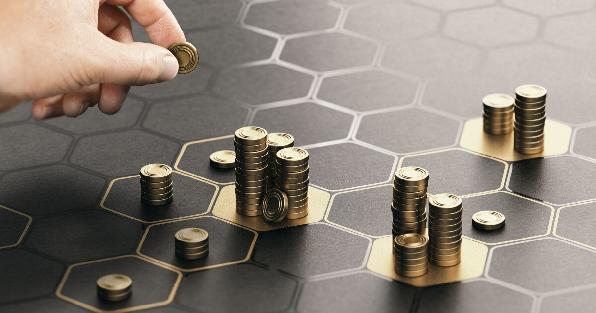 A hand is arranging gold coins on a board with hexagons signifying portfolio diversification and wealth management.