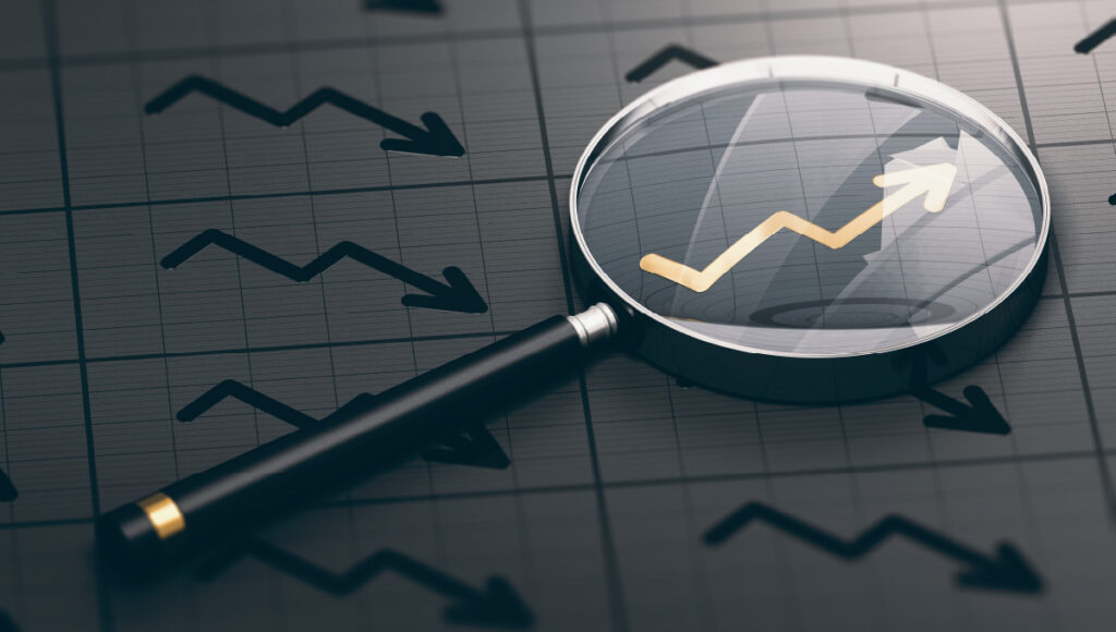 Stock investment represented by a magnifying glass enlarging an arrow trending up.
