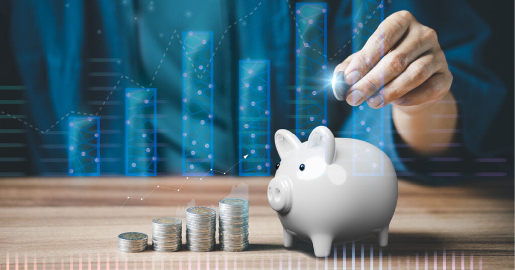 Investing in a Roth retirement account represented by a man putting a coin in a piggy bank with investment charts in the background