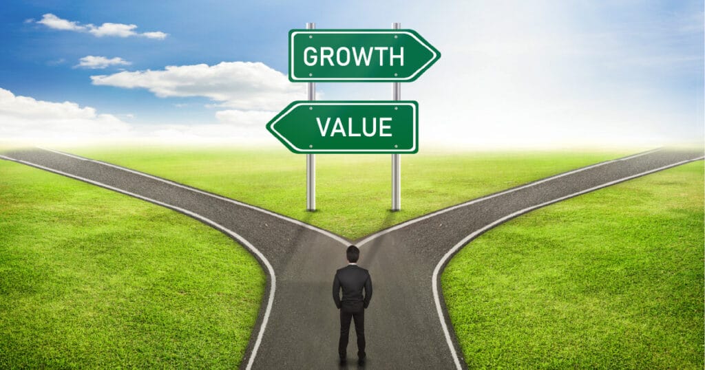 A man standing at a fork in the road, with a sign indicating that “growth” is one direction and “value” is the other, representing growth and value stocks.