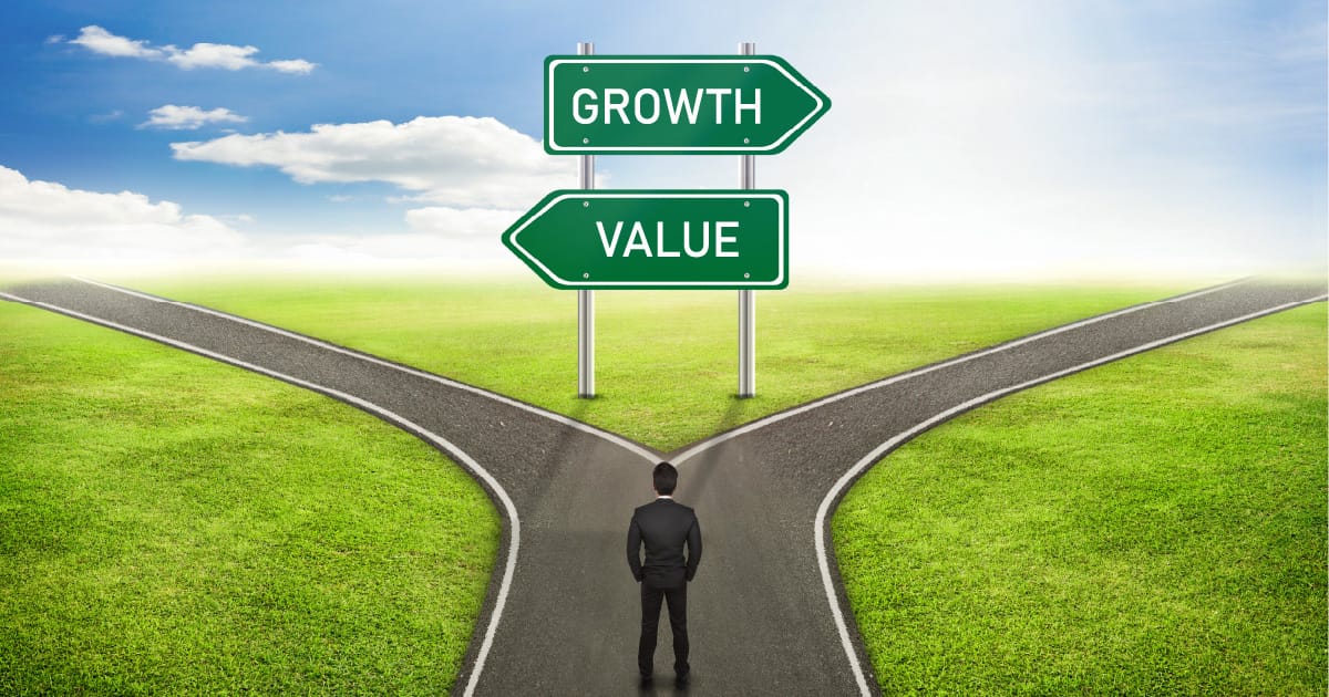 A man standing at a fork in the road, with a sign indicating that “growth” is one direction and “value” is the other, representing growth and value stocks.