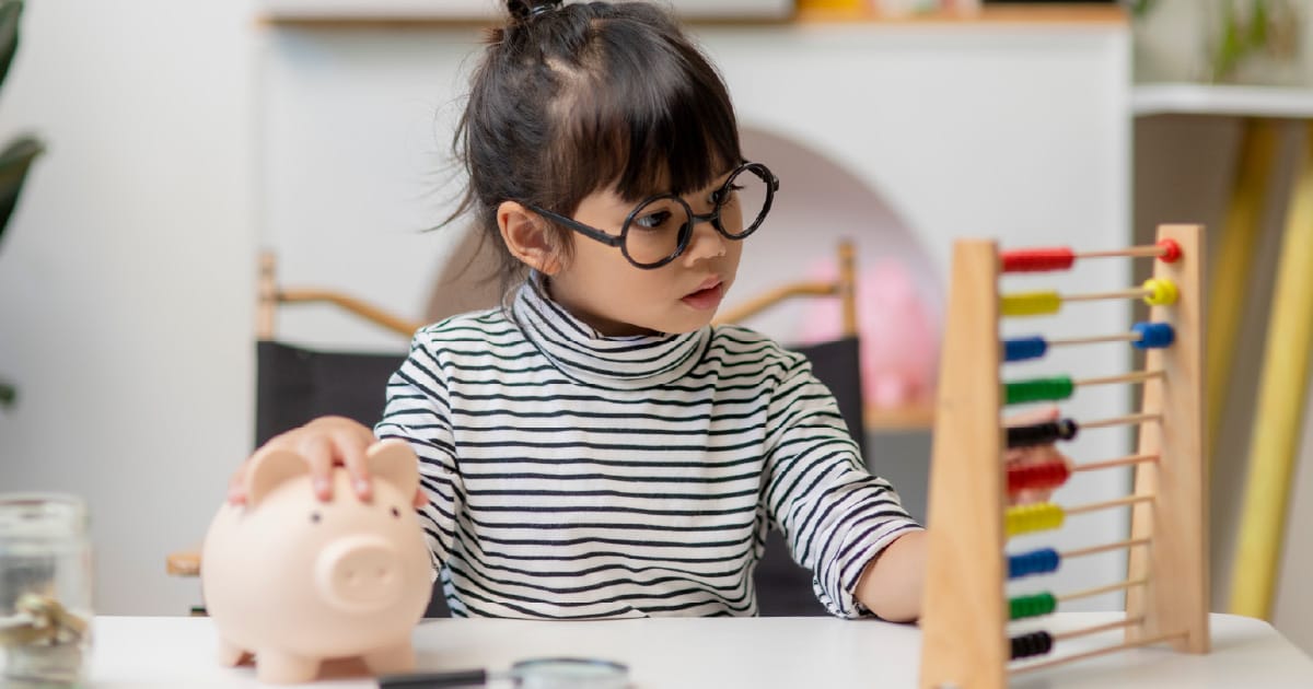 A child counting on an abacus and holding a piggy bank